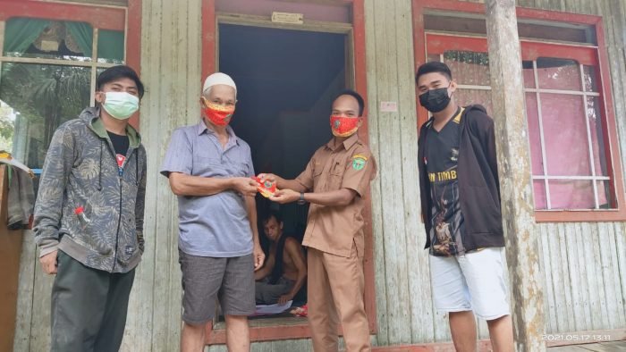 Staff Pemerintahan Kampung Jambuk saat memberikan masker gratis kepada warga di setiap rumah dalam membantu memutus dan mencegah penyebaran Covid-19 semakin meluas. Foto : BorneoFlash.com/HO.