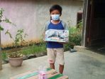 Alviano Dafa Raharjo alias Vino, bocah yatim piatu di Kutai Barat  menggendong mainan yang diberikan para warga yang menaruh empati kepadanya. Foto : BorneoFlash.com/Lilis Suryani.