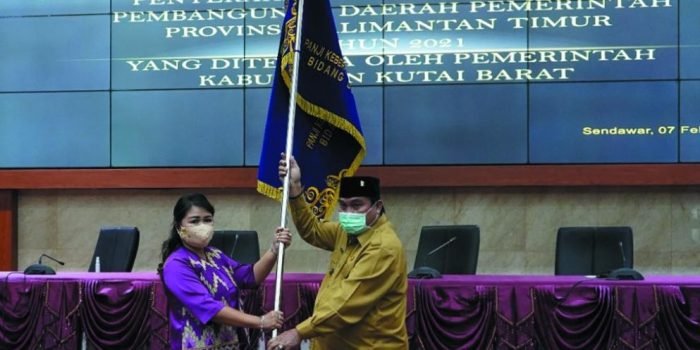 Bupati Kutai Barat FX. Yapan  menyerahkan  panji keberhasilan pembangunan daerah tingkat Provinsi Kaltim tahun 2021 dengan kategori terbaik dI bidang Dekranasda kepada ketua Dekranasda Kutai Barat, Yayuk Seri Rahayu Yapan di gedung ATJ Kompleks perkantora