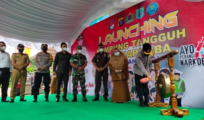 Pemukulan Gong oleh Kapolres Paser AKBP Kade Budiyarta, menandai Desa Tepian Batang sebagai Kampung Tangguh Anti Narkoba, di halaman Kantor Desa Tepian Batang, Selasa (7/6/2022). Foto: HO.