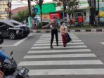 Anggota Dit Samapta Polda Kaltim mengatur lalu lintas dan membantu anak sekolah menyebrang jalan di Kota Balikpapan, Kamis (2/3/2023). Foto: HO/Humas Polda Kaltim.