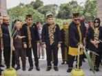 Pj Bupati PPU Muhammad Zainal Arifin bersama perdana menteri Kesultanan Paser H. Lukman Panji (kiri) memotong tebu secara bersamaan sebagai salah satu simbol kehormatan diterima oleh adat menjadi keluarga kehormatan suku Paser di gerbang Rumah Adat Paser Kuta Rekan Tatau Kabupaten PPU Kecamatan Penajam KM. 9, Senin (28/10/2024). Foto: BorneoFlash/Irwan
