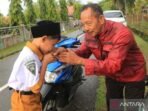 Momen dipagi hari ketika seorang siswa mencium tangan kepada Ayah untuk berpamitan masuk sekolah usai diantarkan sampe ke sekolah. Foto: ANTARA/Syifa Yulinnas/rwa