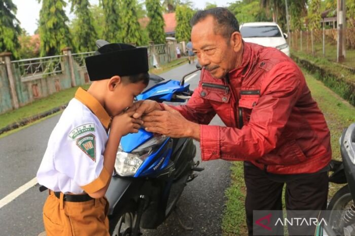 Momen dipagi hari ketika seorang siswa mencium tangan kepada Ayah untuk berpamitan masuk sekolah usai diantarkan sampe ke sekolah. Foto: ANTARA/Syifa Yulinnas/rwa