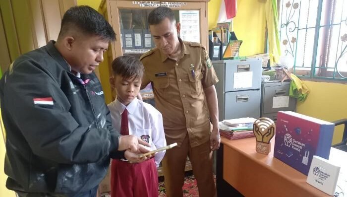 Territory Sales XLSMART area Pekanbaru, Oktamardani (paling kiri), Rayyan Arkan Dikha, yang akrab disapa Dika, bocah "aura farming" (tengah), dan Kepala Sekolah SD Negeri 013 Pintu Gobang Kari Kuansing, Ropis Indra, S.Pd.I (paling kiri), saat menerima Program Gerakan Donasi Kuota (GDK) di SD Negeri 013 Pintu Gobang Kari Kuansing, pada Senin (11/8/2025). Foto: HO/ XLSMART