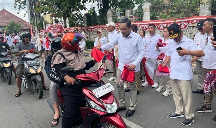 Wakil Gubernur Kaltim, Seno Aji saat membagikan bendera merah putih pada kendaraan yang lewat di kawasan Taman Samarendah, Jalan Bhayangkara, pada Sabtu (16/8/2025). Foto: BorneoFlash/Nur Ainunnisa
