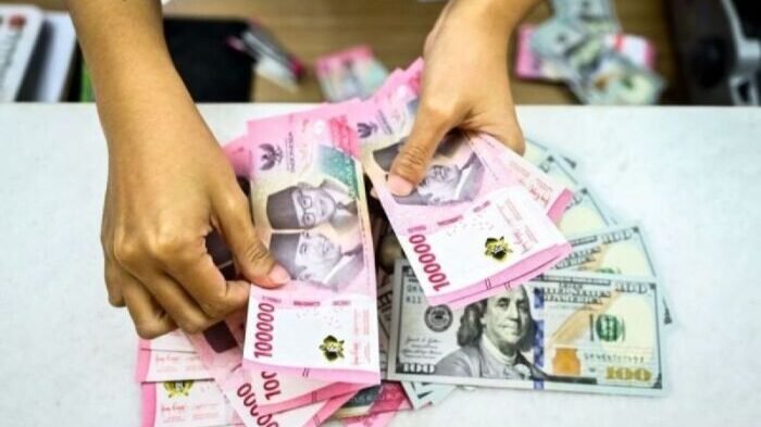 Seorang petugas di gerai penukaran mata uang asing di Jakarta menghitung pecahan dolar AS dan rupiah. Dok. Foto: ANTARA/Rivan Awal Lingga/tom.