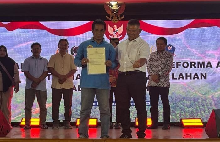 Deputi Bidang Pemanfaatan Tanah dan Kerja Sama Usaha Badan Bank Tanah, Hakiki Sudrajat saat menyerahkan sertipikat tanah kepada masyarakat penerima manfaat reforma agraria di Kabupaten Penajam Paser Utara (PPU), Kalimantan Timur, di Kantor Bupati PPU, pada Kamis (25/9/2025). Foto: BorneoFlash/Niken Sulastri
