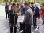 Bupati Kutim, Ardiansyah Sulaiman memberikan simbolis penghargaan kepada Nur Salim, Manager ULP Sangatta, dalam acara Reward Pajak Daerah 2025 yang digelar Bapenda Kutim, bertepatan dengan peringatan HUT ke-26 Kabupaten Kutai Timur, Minggu (12/10/2025). Foto: HO/PLN UID Kaltimra