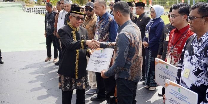 Bupati Kutim, Ardiansyah Sulaiman memberikan simbolis penghargaan kepada Nur Salim, Manager ULP Sangatta, dalam acara Reward Pajak Daerah 2025 yang digelar Bapenda Kutim, bertepatan dengan peringatan HUT ke-26 Kabupaten Kutai Timur, Minggu (12/10/2025). F