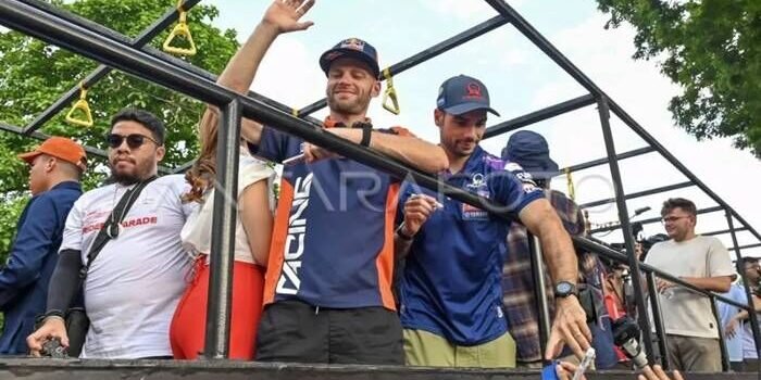 Pembalap Prima Pramac Yamaha MotoGP Miguel Oliveira (kanan) bersama pembalap Red Bull KTM Factory Racing Brad Binder (kiri) melambaikan tangannya saat mengikuti MotoGP Riders Parade di Jalan Udayana, Mataram, NTB, Rabu (1/10/2025). Parade yang diikuti 10 