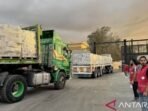 Arsip Foto - Staf Bulan Sabit Merah Mesir berdiri di dekat truk-truk pengangkut bantuan kemanusiaan saat memasuki Jalur Gaza dari sisi Mesir di perbatasan Rafah, Palestina, pada Minggu (12/10/2025). Foto: ANTARA/Xinhua/Ali Mostafa/aa