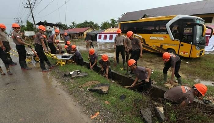 Personel Brimob Kepolisian Negara Republik Indonesia (Polri) membersihkan drainase di pinggir jalan nasional Banda Aceh - Medan di Aceh Tamiang, Aceh, Minggu (28/12/2025). Polri menetapkan Kabupaten Aceh Tamiang sebagai prioritas utama penguatan personel dan pembersihan sarana prasarana dalam penanganan bencana banjir bandang di Provinsi Aceh. FOTO : ANTARA/Irwansyah Putra/foc.