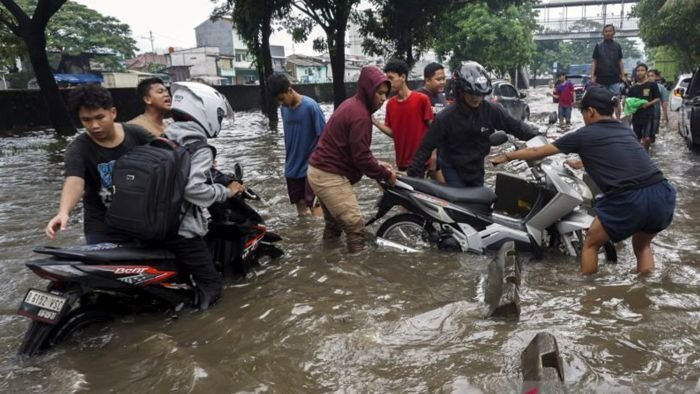 Warga membantu pengendara sepeda motor yang mogok saat menerobos banjir di Jalan Daan Mogot, Jakarta, Kamis (22/1/2026). Banjir setinggi 50-60 cm akibat hujan berintensitas tinggi serta buruknya sistem drainase tersebut membuat sejumlah kendaraan mogok dan lalu lintas terganggu. Foto: BorneoFlash/Antara Foto/Ika Maryani